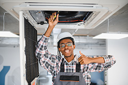 Spring Lake air conditioner repair employee giving thumbs up while working on ducts